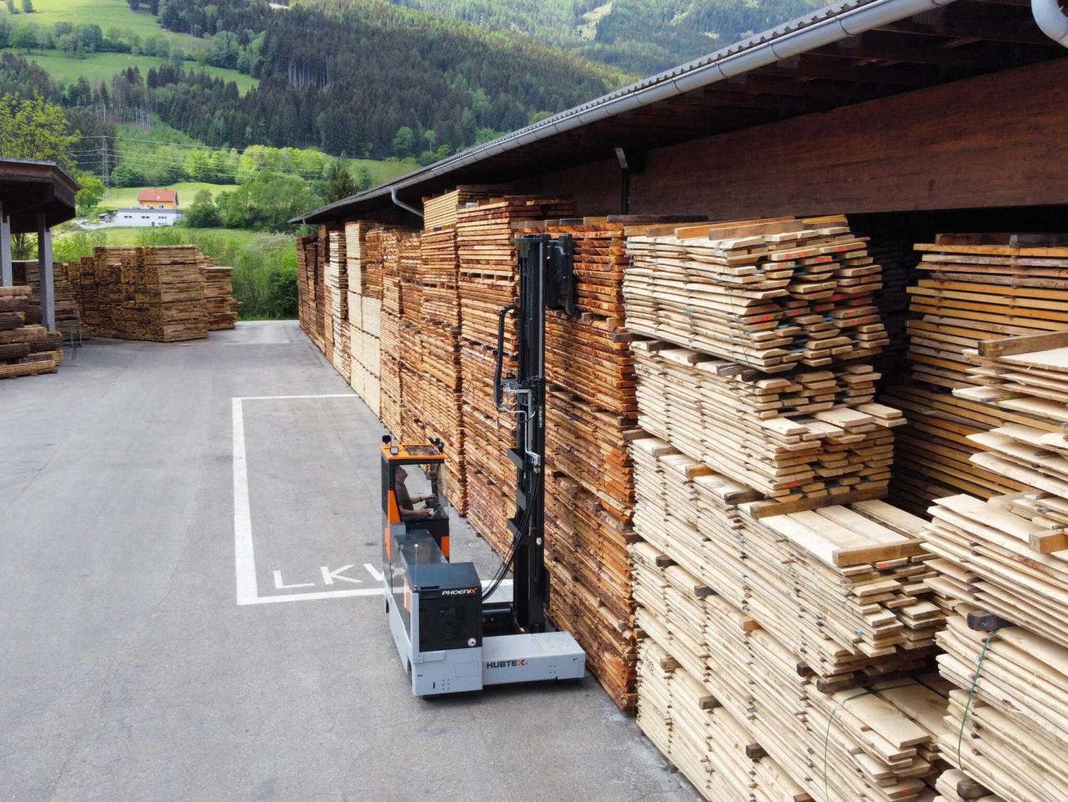 HUBTEX PHOENIX meerwegheftruck transporteert hout in houtopslag bij zagerij