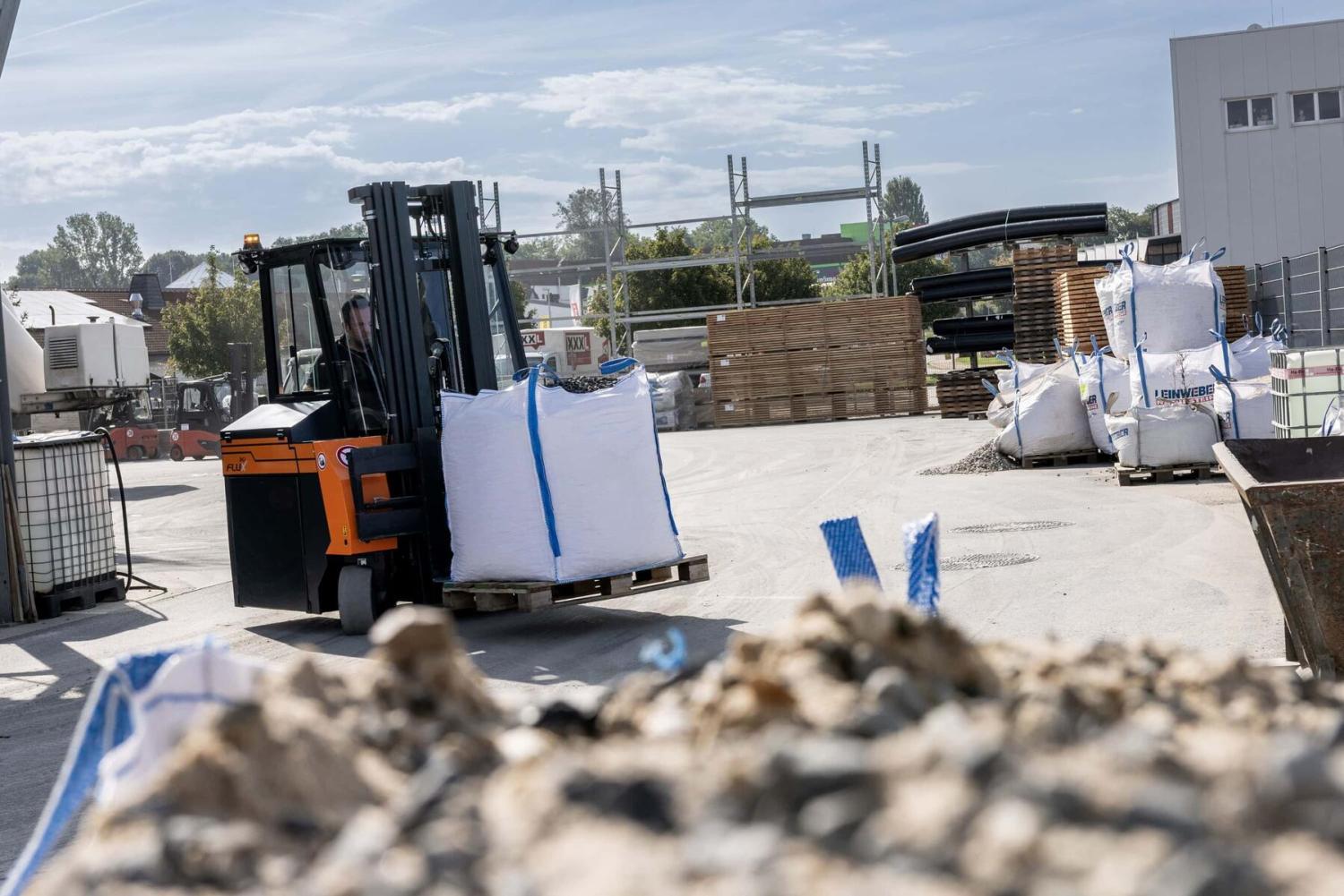 HUBTEX FLUX 30 meerwegheftruck vervoert big bag met bulk materiaal op opslagterrein