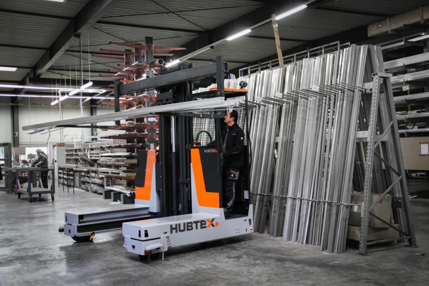 HUBTEX DS27 meerwegheftruck in magazijn met lange metalen buizen