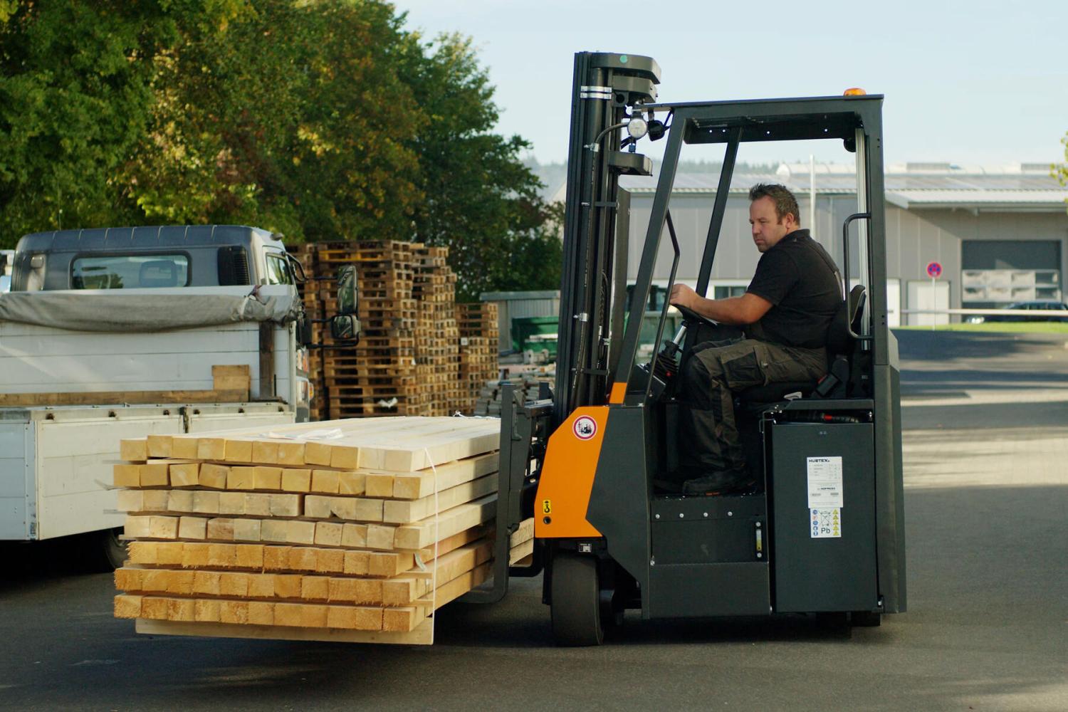 HUBTEX FLUX meerwegheftruck vervoert lange houten planken op industrieterrein