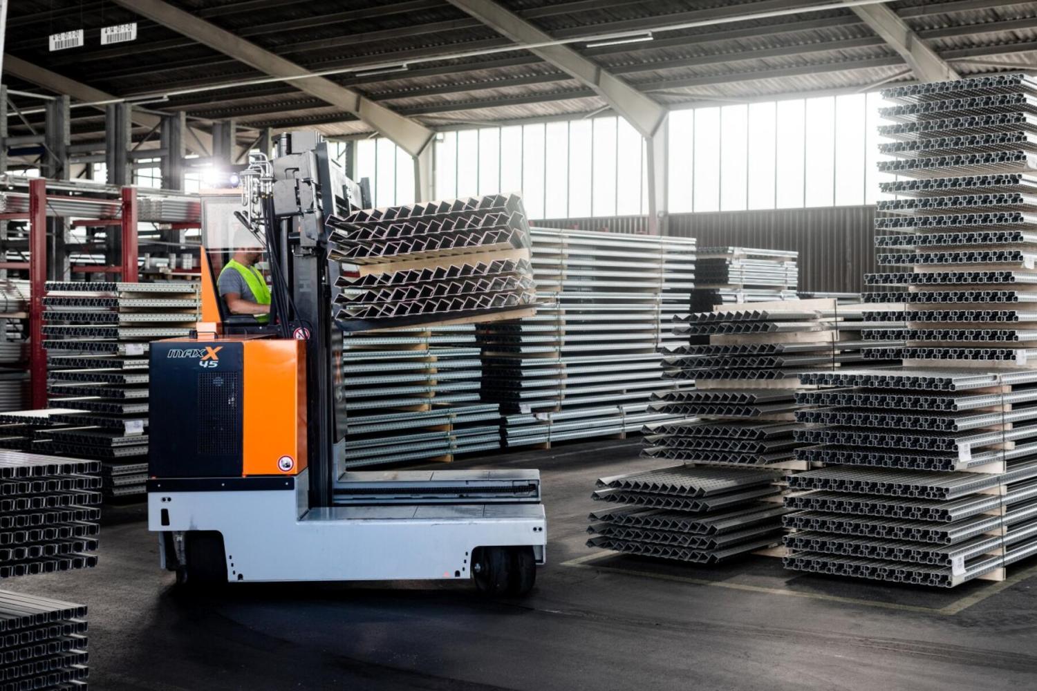 HUBTEX MAXX 45 meerwegtruck transporteert gestapelde stalen profielen in industriële hal