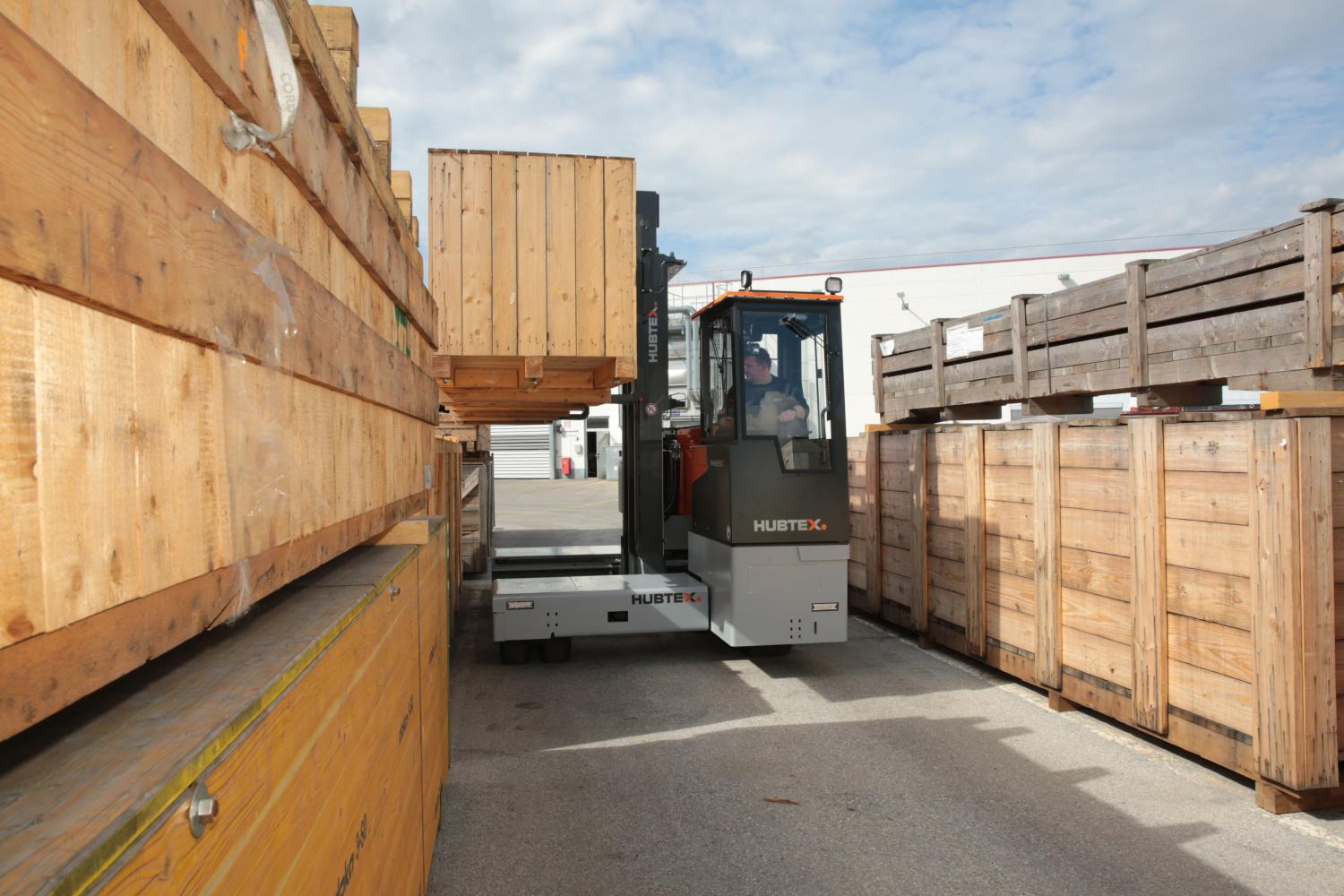 HUBTEX meerwegheftruck transporteert houten kisten in buitenopslag
