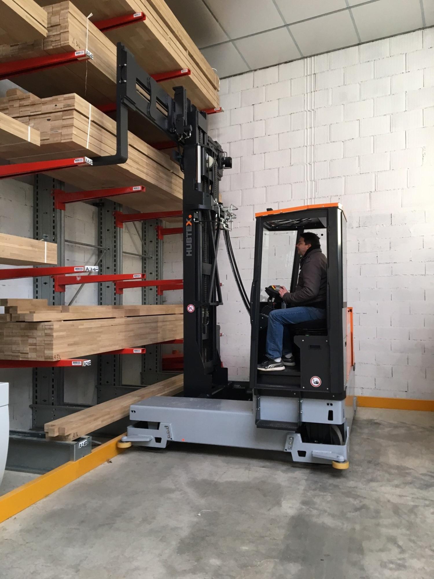 HUBTEX MAXX meerwegheftruck plaatst houten balken in draagarmstelling in magazijn