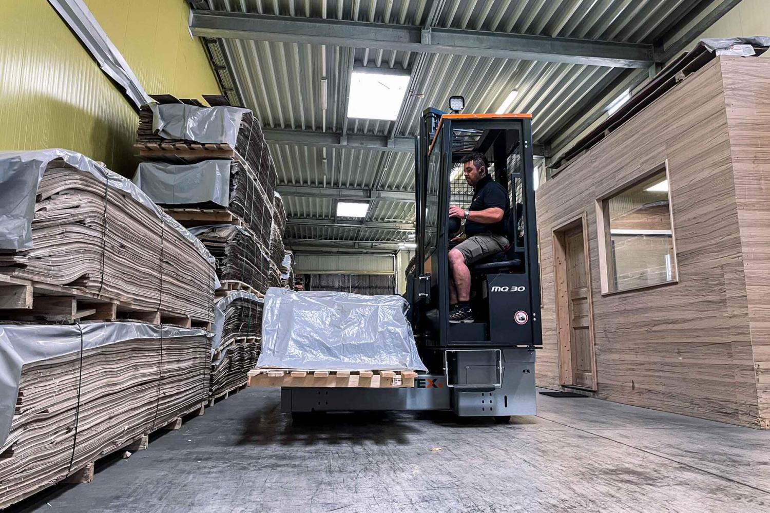 HUBTEX PHOENIX meerwegheftruck transporteert lange houten planken in houtmagazijn
